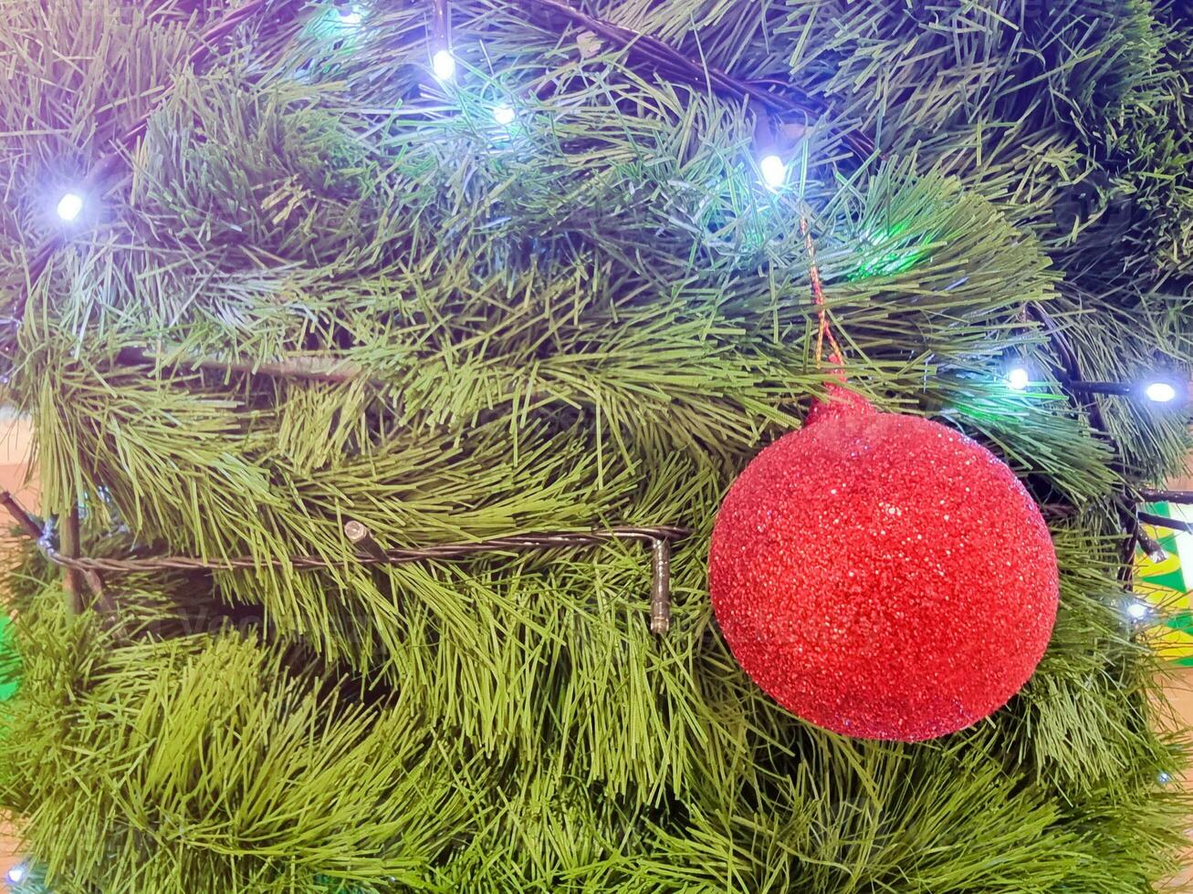 glücklich Neu Jahr Schönheit Zuhause Innere mit Weihnachten Baum und Girlanden klein rot Bälle. verschwommen Beleuchtung golden Bokeh Grün Blätter. fröhlich Weihnachten Hintergrund. foto