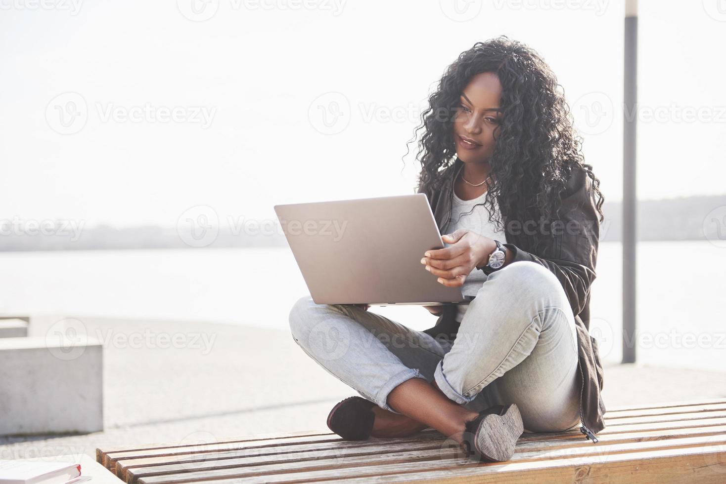 junge Frau auf der Straße, die am Laptop arbeitet foto