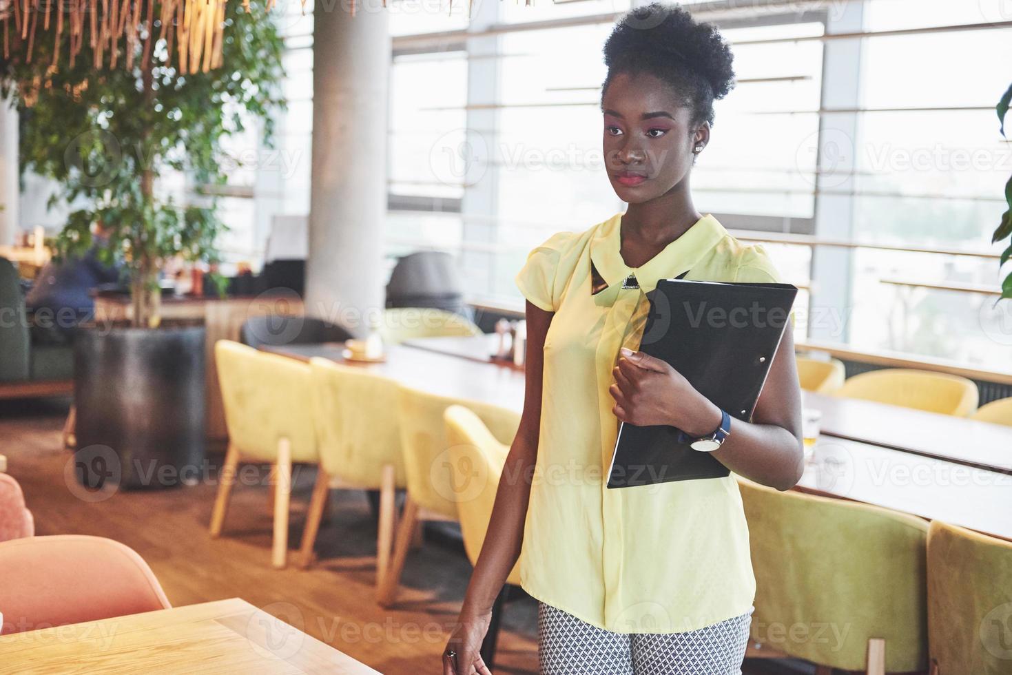 Afroamerikanische Geschäftsfrau steht mit einem Ordner in der Hand foto