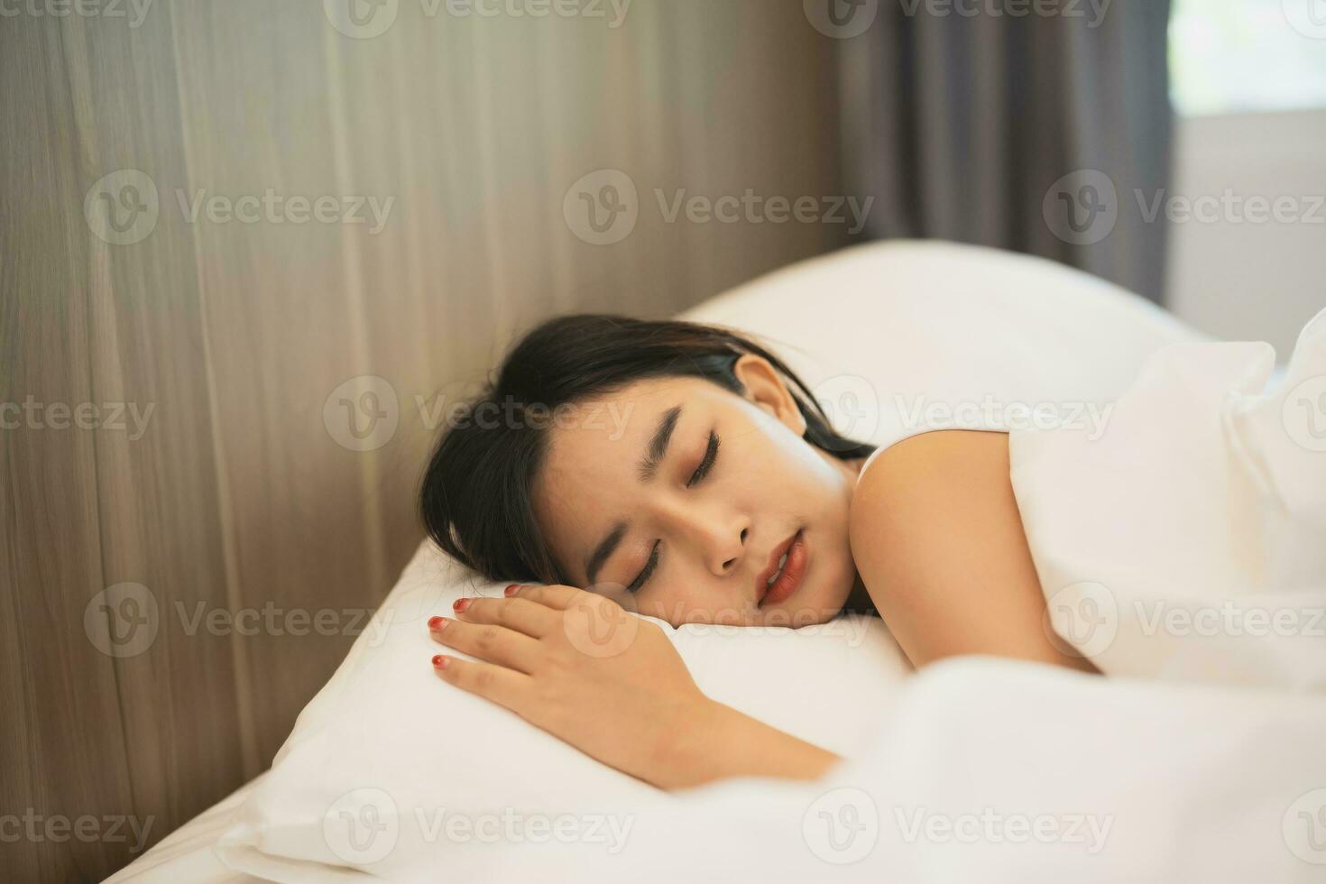 asiatisch Frau Schlafen mit Clever Uhr zeigen Verfolgung Herzschlag Monitor im komfortabel Bett mit seidig Bettwäsche beim Nacht Licht. Frauen Lügen im Bett und behalten Augen geschlossen während bedeckt mit Decke. foto