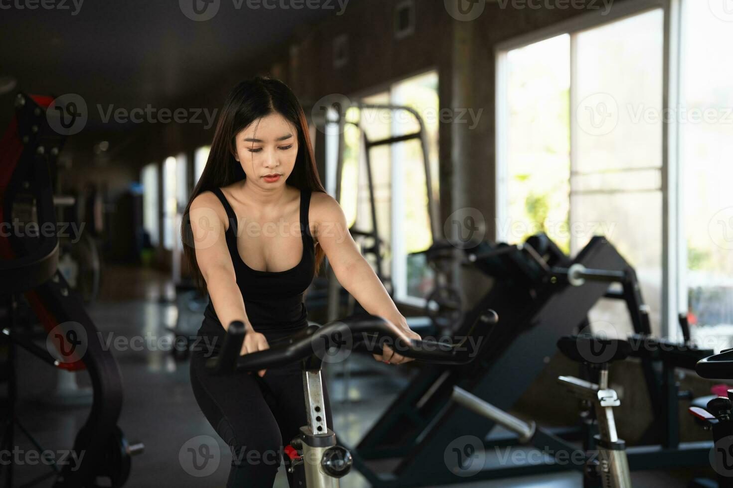 asiatische Sportlerin, die im Fitnessstudio auf einem Fahrrad trainiert, Entschlossenheit, Gewicht zu verlieren, macht sie gesund. Heimtrainer Frau Fitness Sportkonzept. foto