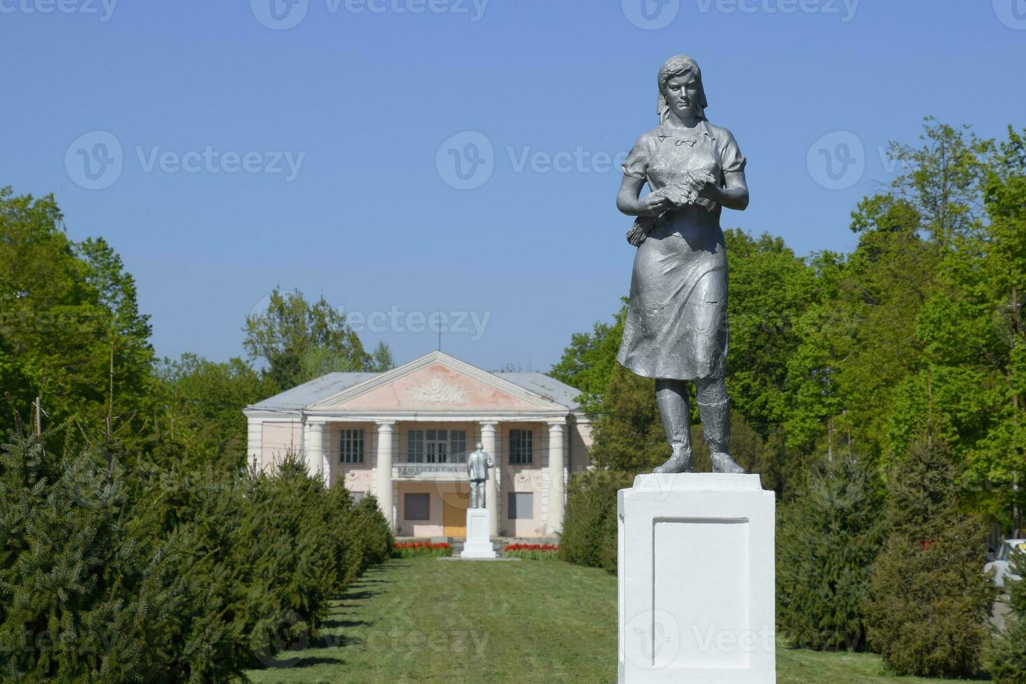 Statue von ein kollektiv Farmer auf ein Sockel. das Erbe von das Sowjet Epoche. ein Blume Bett mit Tulpen und jung Bäume im das Dorf von oktjabrski. krasnodar krai, krasnoarmeisky Bezirk. foto