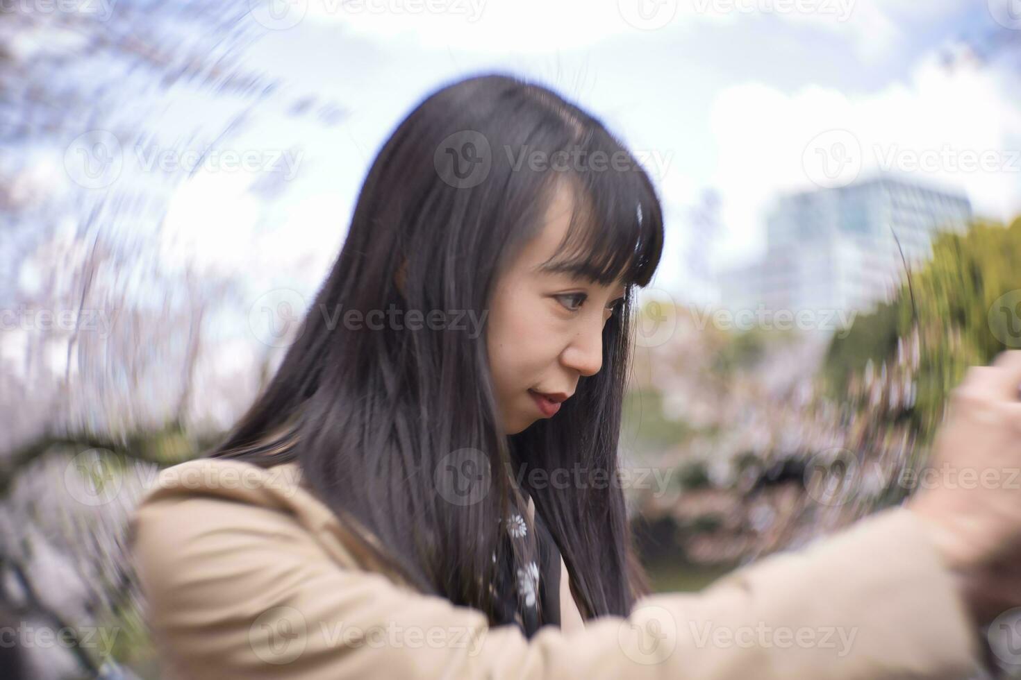 ein Porträt von japanisch Frau Schießen durch spiegellos Kamera hinter Kirsche blühen foto