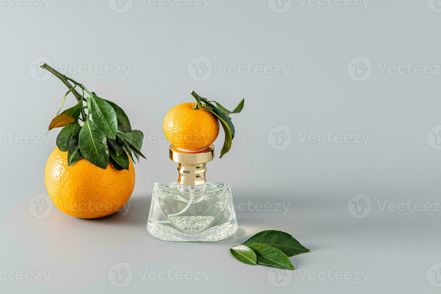 elegant Kristall Flasche von Damen Parfüm mit das Aroma von zart frisch Zitrusfrüchte auf ein grau Hintergrund mit Mandarine Früchte. Präsentation. foto