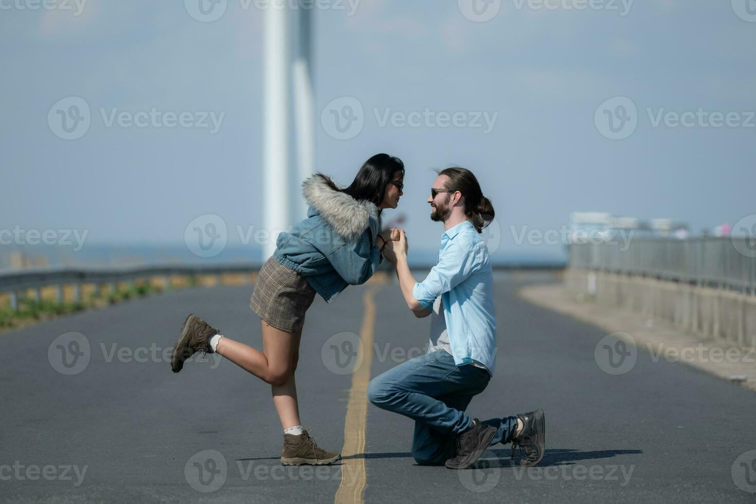 auf das Straße, ein jung Paar schlägt vor zu jeder andere, mit Wind Turbinen im das Hintergrund. foto