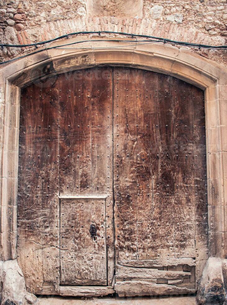 braun hölzern alt Tür gemacht von Lamellen Foto. grau Backstein Mauer mittelalterlich Haus. Eingang mit Schlüsselloch und Eisen Armaturen foto