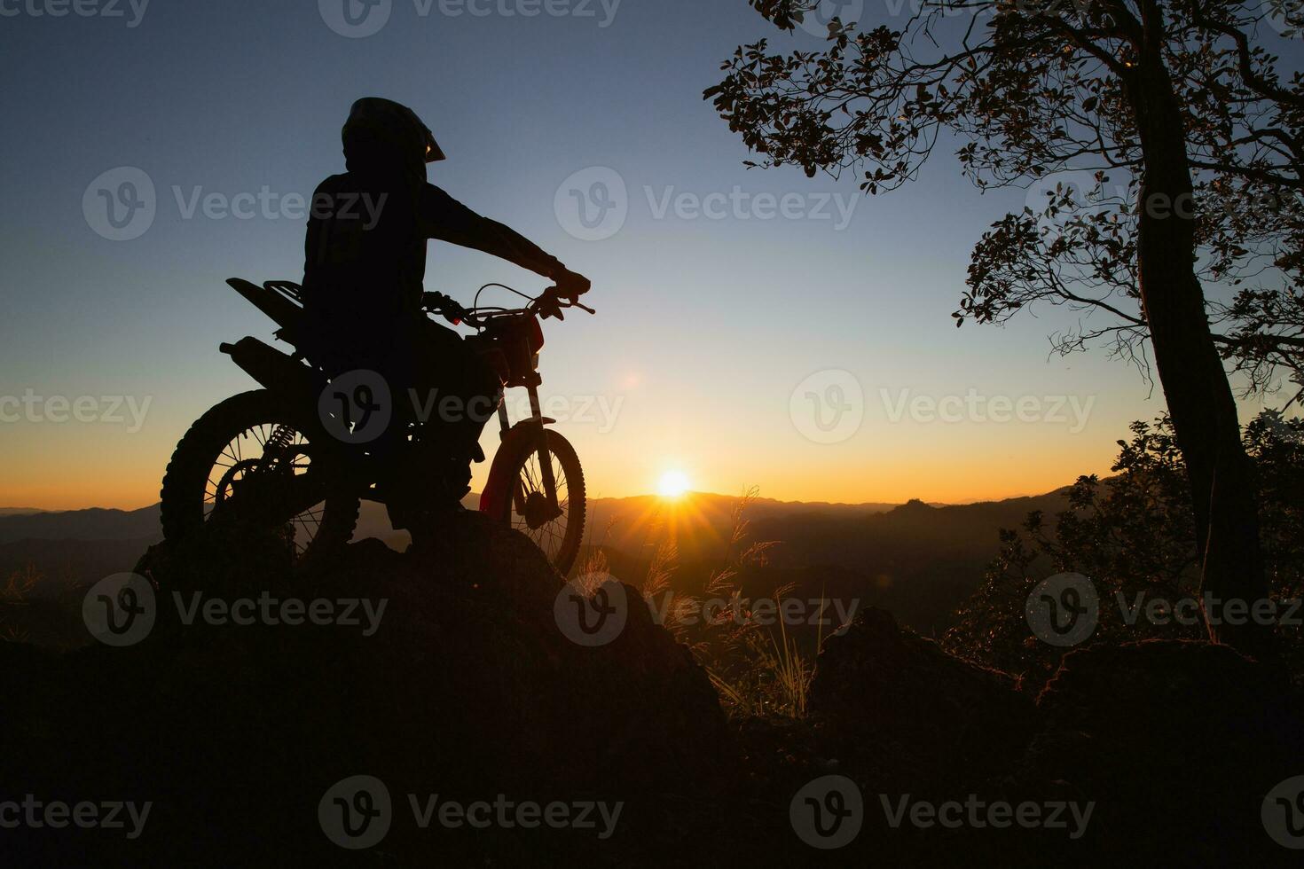 Mann mit Moto-Cross Fahrrad gegen schön Beleuchtung, Silhouette von ein Mann mit Moto-Cross Motorrad auf oben von Felsen hoch Berg beim schön Sonnenuntergang, Enduro Motorrad Reise Konzept. foto