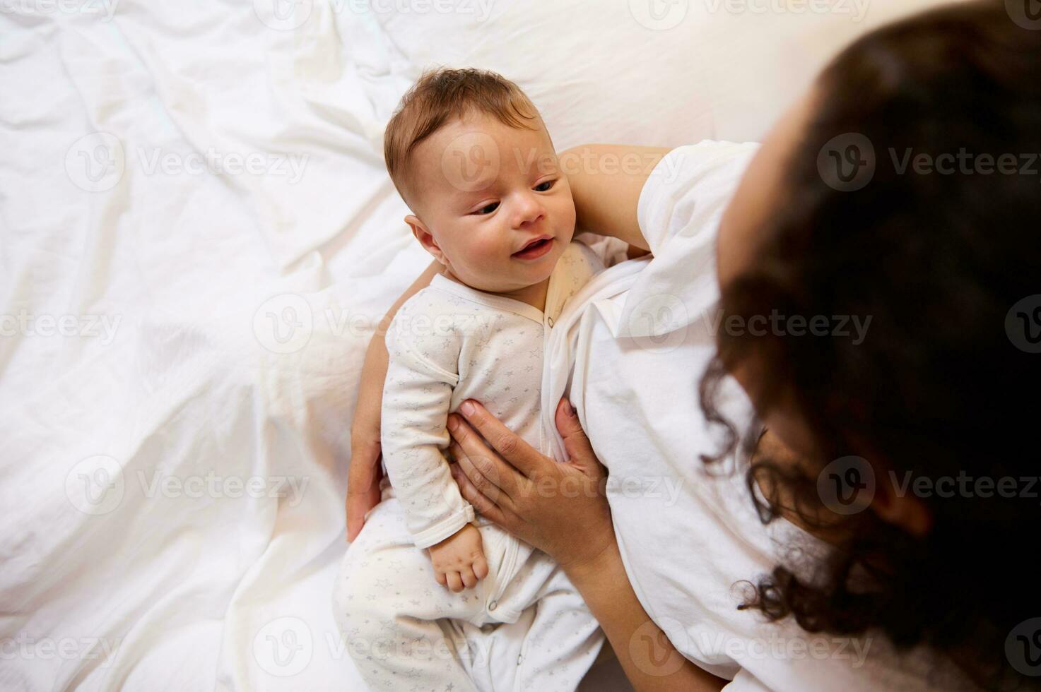 Aussicht von über von kaukasisch Kind, bezaubernd Neugeborene Baby im das Hände von ein Frau, glücklich liebend Mutter sanft halten, umarmen, streicheln und umarmen ihr Baby Junge. Kindheit und Mutterschaft Konzept foto
