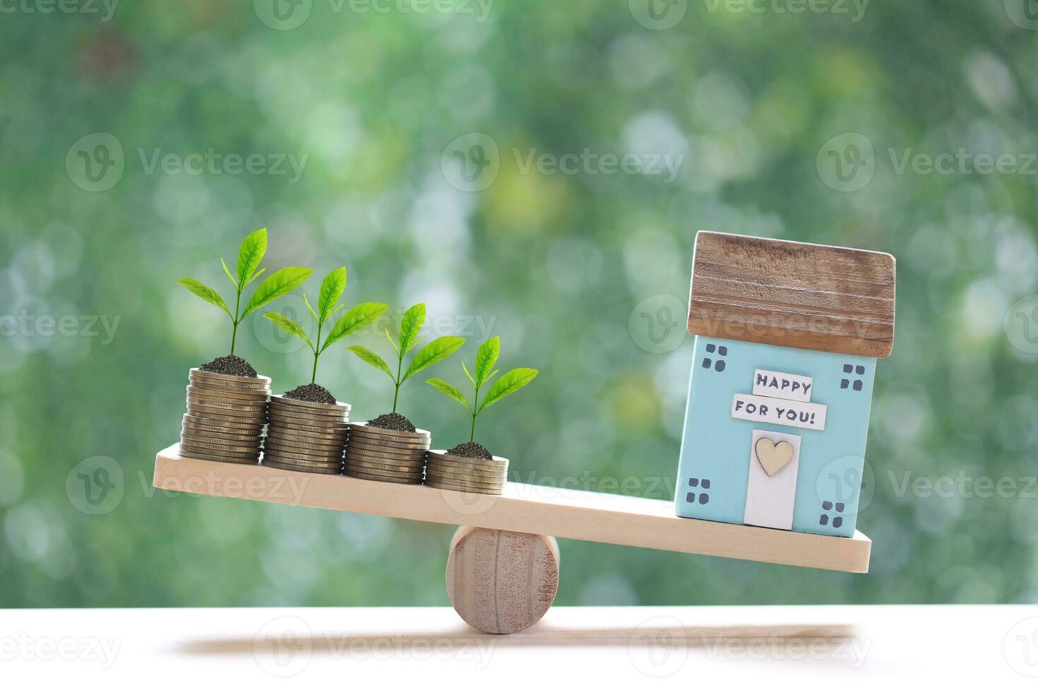 Modell- Haus und Stapel von Münzen Geld auf Holz Rahmen Wippe mit natürlich Grün Hintergrund, Geschäft Investition und echt Nachlass Konzept foto