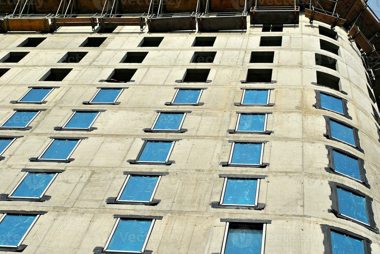 hoch erhebt euch Gebäude unter Konstruktion. Installation von Glas Fassade Paneele auf ein verstärkt Beton Struktur. foto