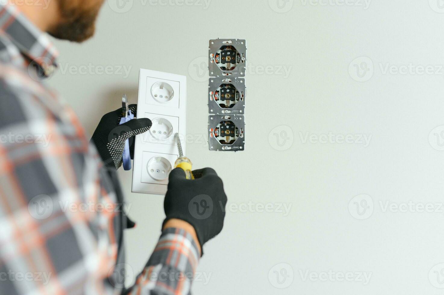 Elektriker mit Schraubendreher reparieren Leistung Steckdose im Zimmer foto