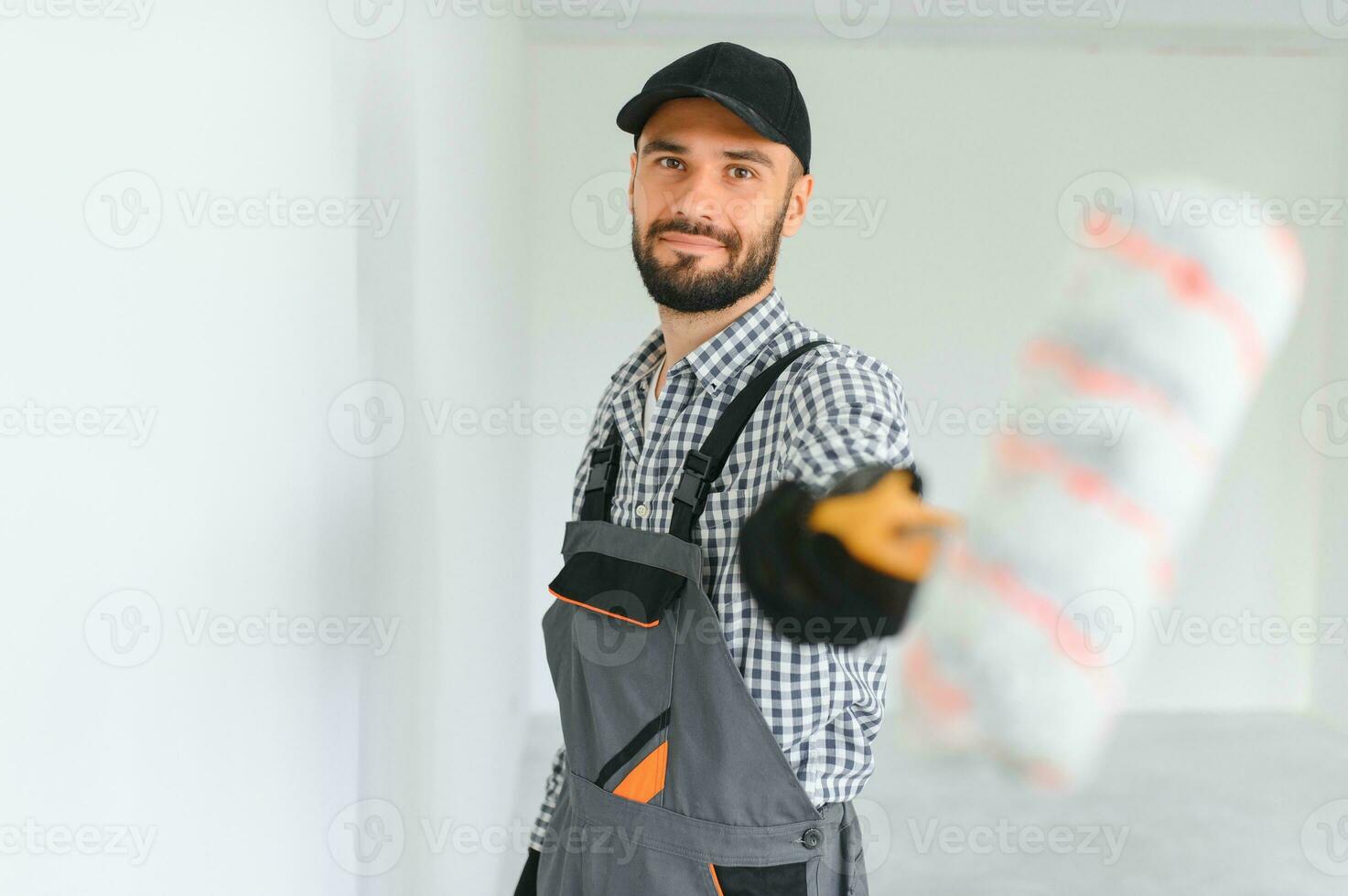 jung Fachmann Arbeiter im Uniform Stehen mit Farbe Rolle. foto