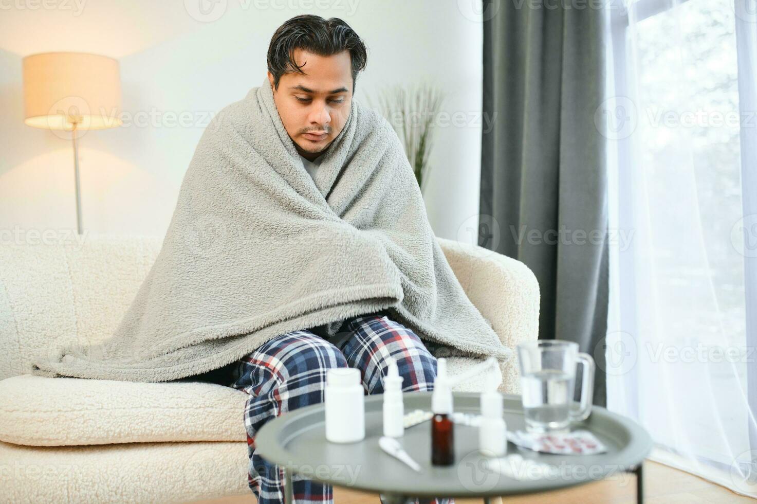 krank indisch Mann im Plaid sitzen allein Zittern von kalt. ungesund arabisch Kerl sitzen auf Stuhl Gefühl Beschwerden Versuchen zu Erwärmen oben foto