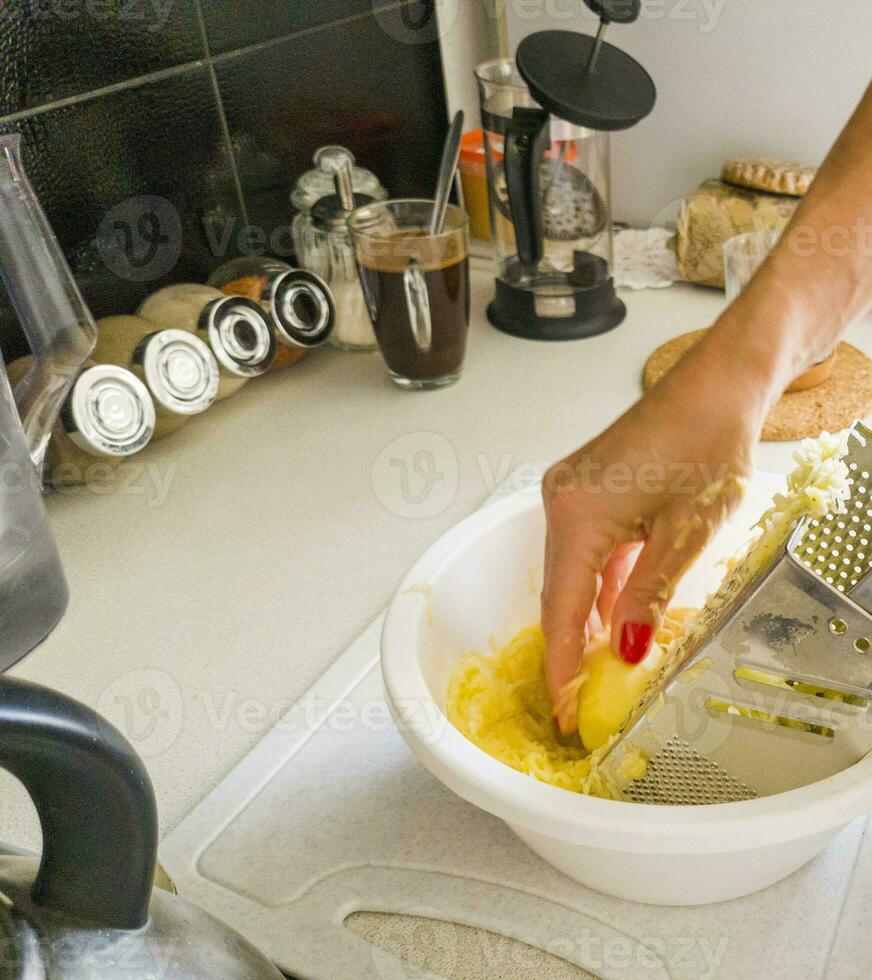 Frau Mahlen Kartoffeln auf das Reibe im das Küche. Essen foto