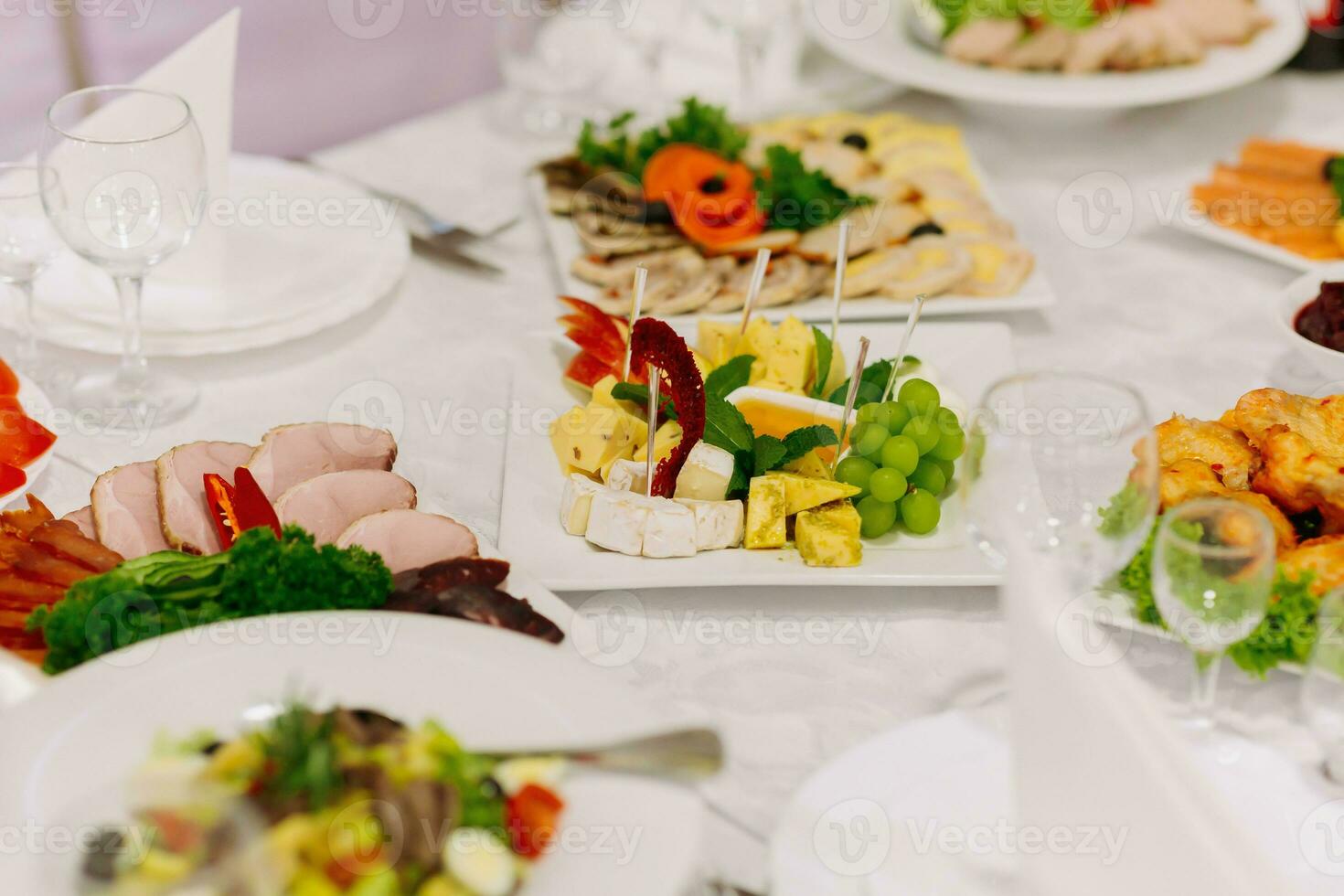 Buffet Tabelle beim ein Hochzeit. Käse Platte. Sortiment von Kanapees. Bankett Service. Essen, Snacks mit Käse, Schinken, Prosciutto und Frucht. Caesar Salat. Glas Brille. Silber Tabelle setzt. foto