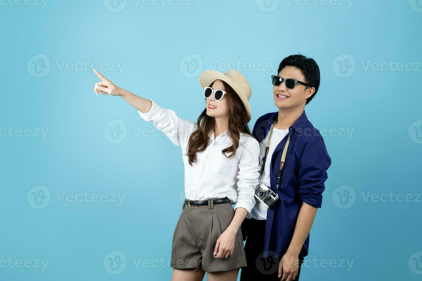 glücklich asiatisch Tourist Paar zeigen im Kopieren Raum beim Ferien Ziel Stehen isoliert auf Blau Hintergrund. foto