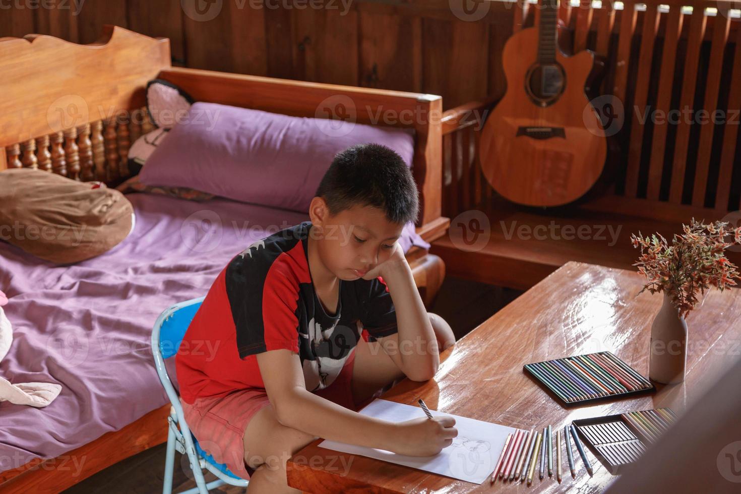 ein Junge sitzt in seinem Haus und zeichnet und malt. foto