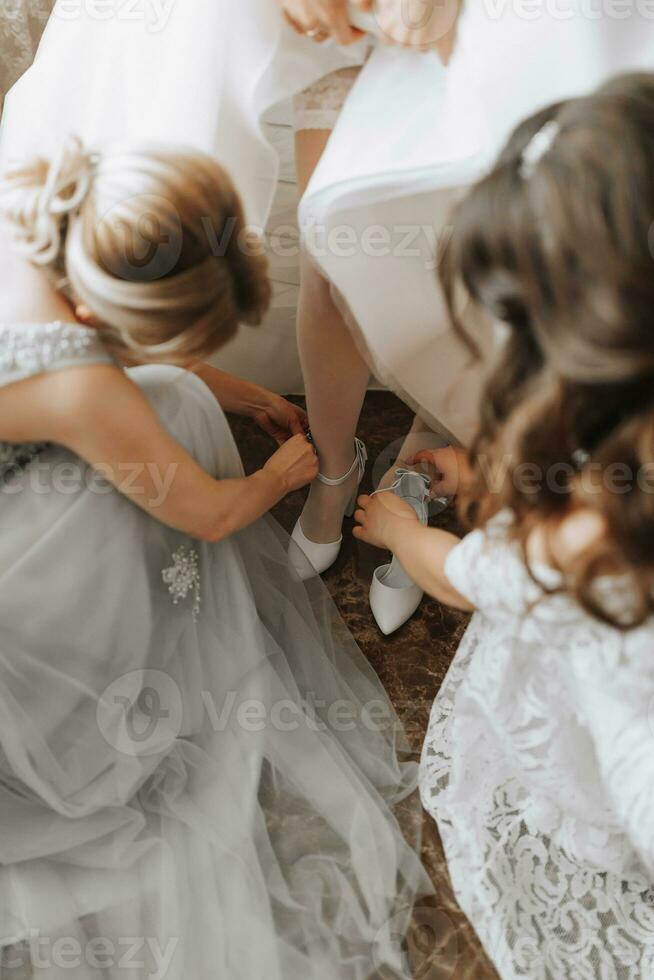 Freundinnen Hilfe das Braut stellen auf ihr Hochzeit Schuhe. schön weiblich Beine Nahansicht foto