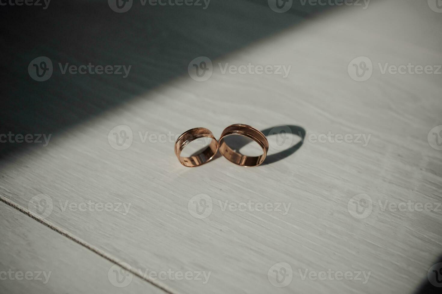 Hochzeit golden Ringe im schön Tageslicht, auf ein Weiß hölzern Hintergrund. Schatten. Hochzeit Zubehör. foto