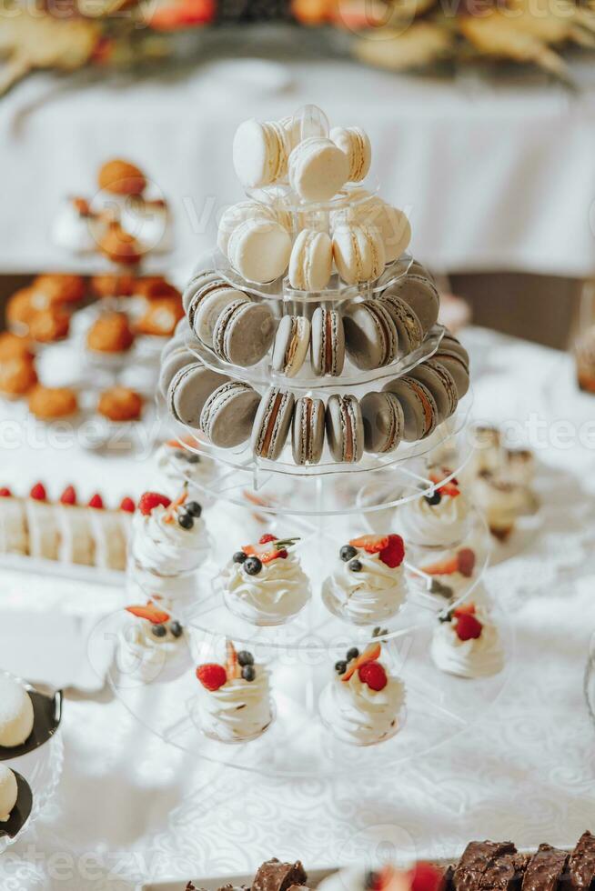 Süßigkeiten Bar. Tabelle mit Süßigkeiten, Süßigkeiten, Nachtisch. Kuchen und Beeren im das Süßigkeiten Bar. Süßigkeiten Bar mit köstlich Mini Kuchen, selektiv Fokus foto