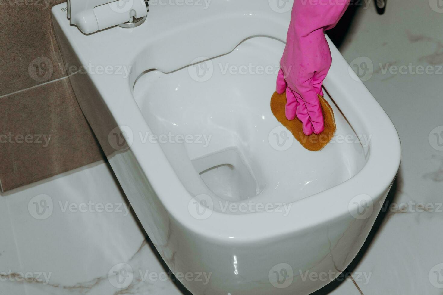 ein Frau reinigt das Toilette mit ein Toilette Gewebe. ein Hausfrau wie ein Toilette Reiniger. sauber das Toilette zum Sauberkeit und Hygiene. Toilette Reinigung Reinigung Bedienung Konzept. Rosa Gummi Handschuh foto