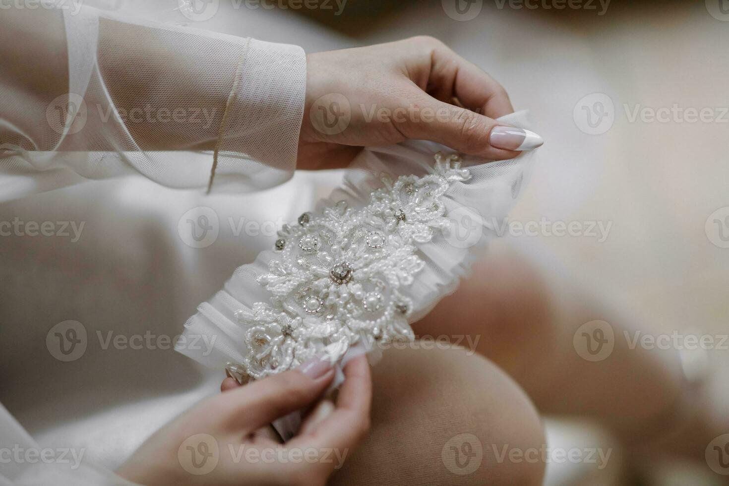 Hochzeit Einzelheiten. das Braut hält ihr Hochzeit Band, welche ist dekoriert mit Perlen und Spitze. schön Hände. Französisch Maniküre foto