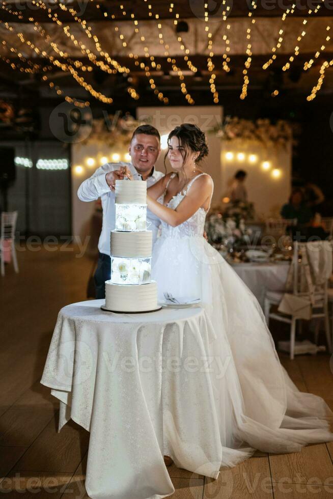 Jungvermählten schneiden glücklich die Hochzeitstorte an und probieren sie foto