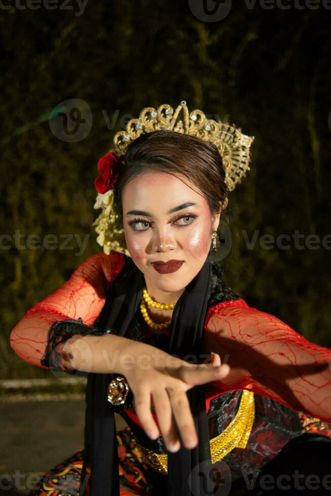 ein asiatisch Tänzer im ein rot Kostüm posiert sehr flexibel auf ein Bühne foto