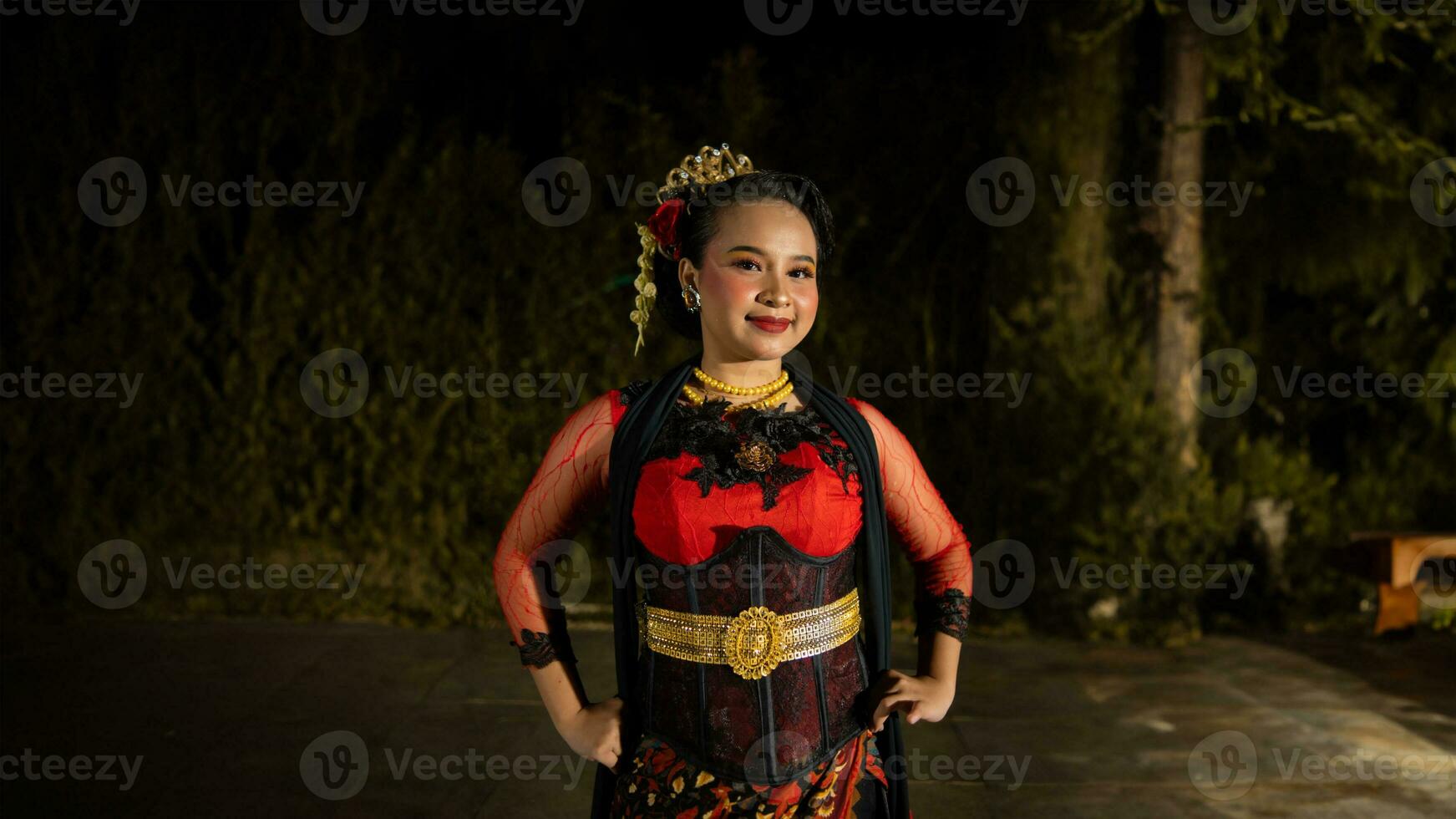 ein indonesisch Tänzer strahlt Charme Das zieht an das Beachtung von das Publikum während das Performance mit ihr rot Kleid foto
