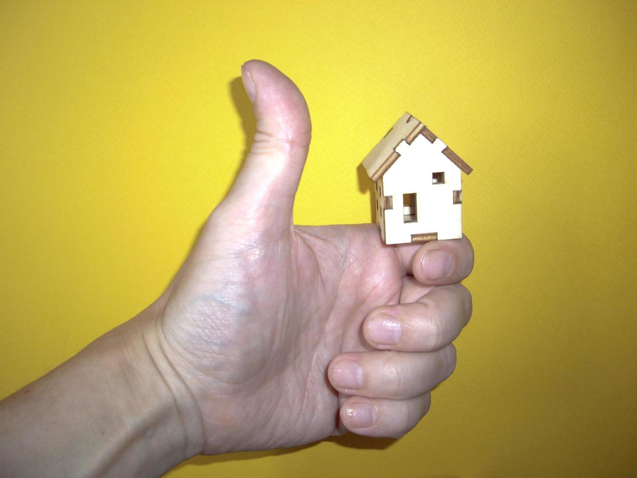 kleines Holzhaus in der Hand eines Mannes auf gelbem Hintergrund foto