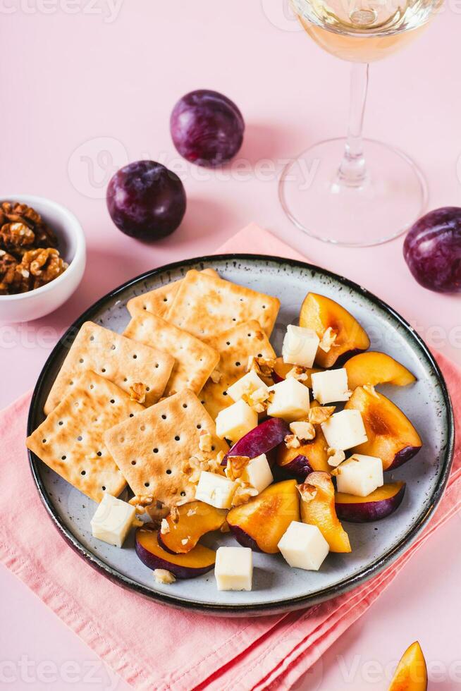 Abendessen zum Mädchen, Kekse, Käse, Pflaumen und Walnüsse auf ein Teller auf das Tabelle Vertikale Aussicht foto