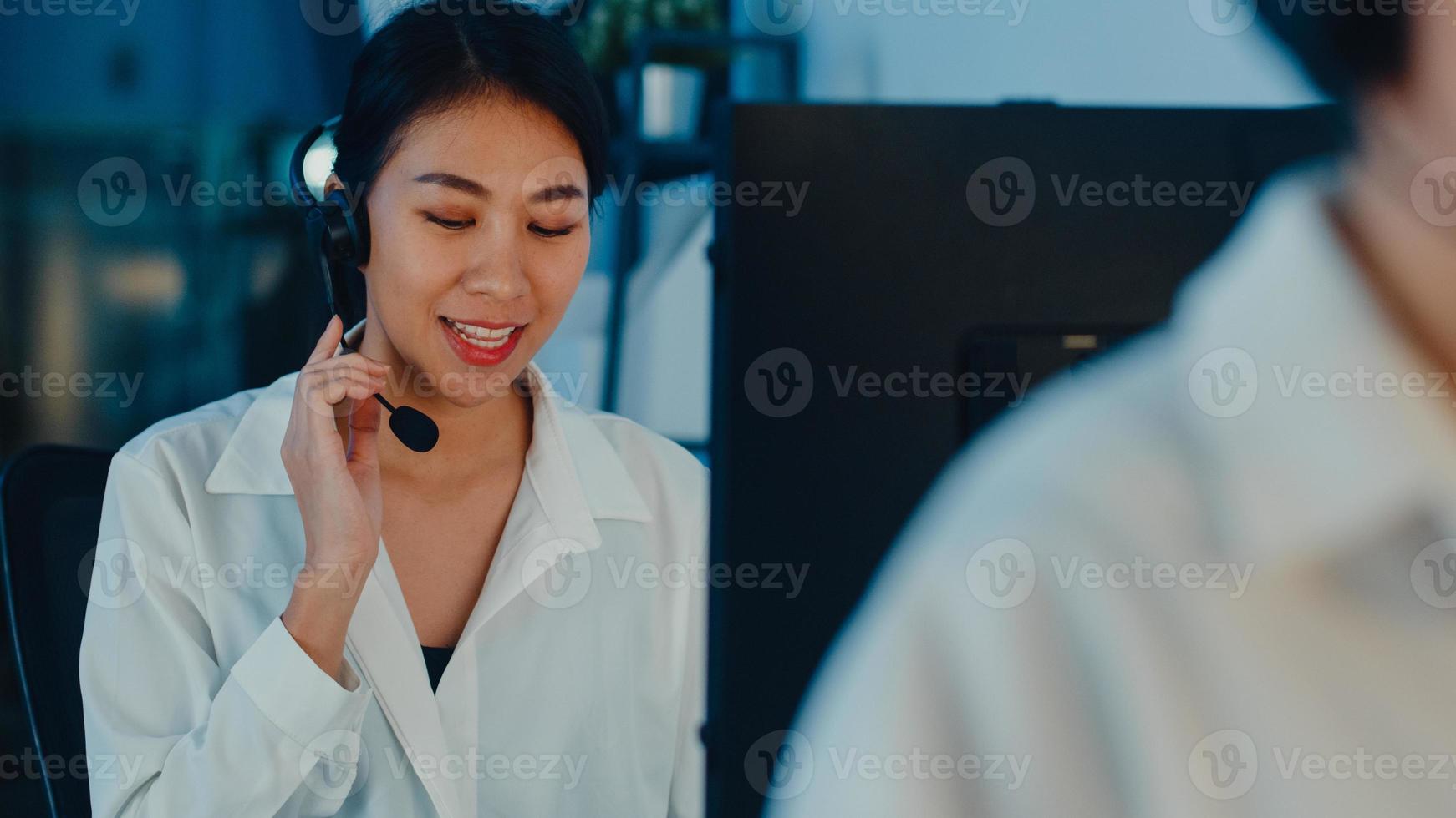 Millennial Asia Young Call Center Team oder Customer Support Service Executive mit Computer- und Mikrofon-Headset, das technische Unterstützung im Late-Night-Büro verwendet. Telemarketing- oder Verkaufsjobkonzept. foto