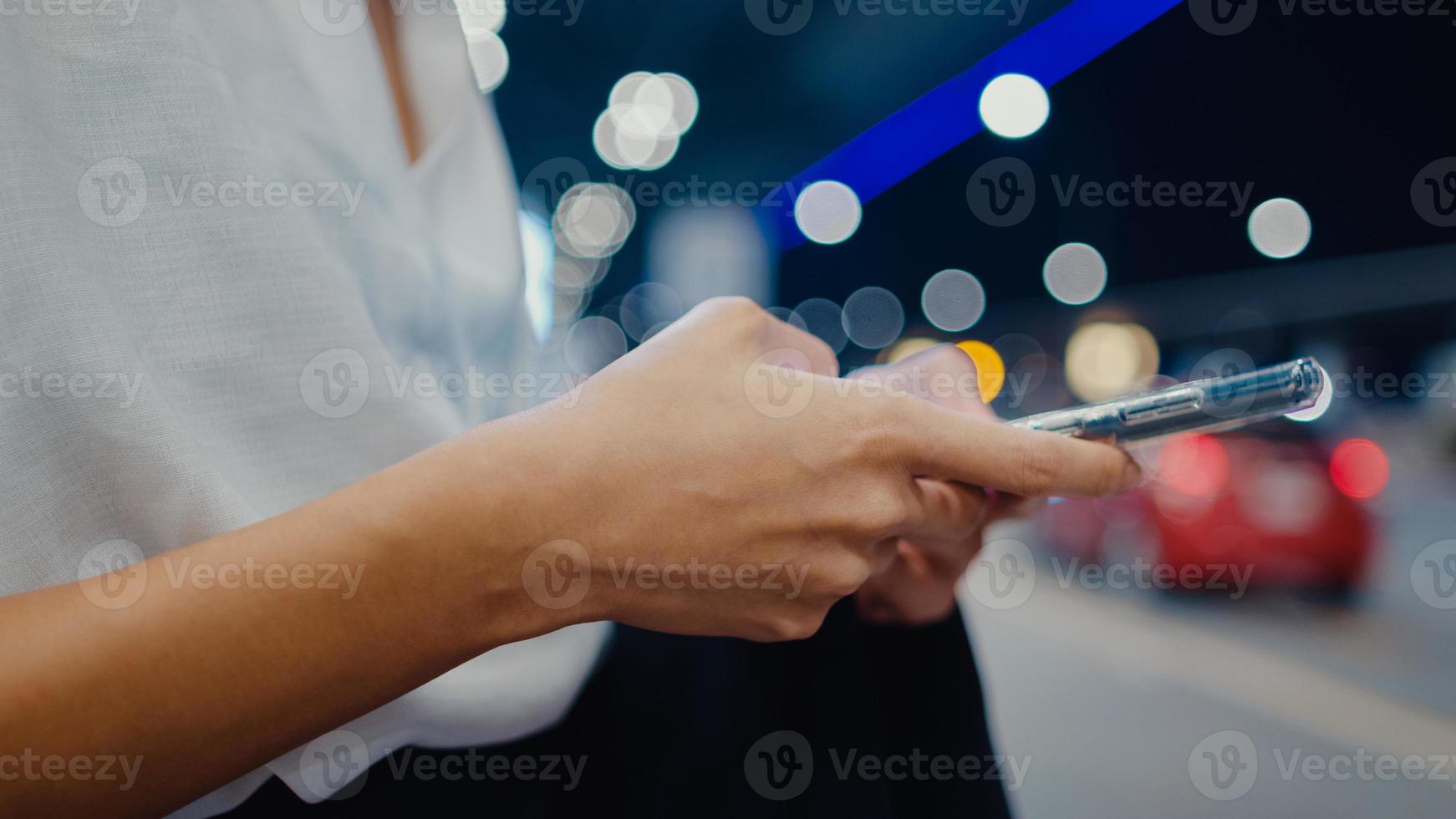 Nahaufnahme asiatische Geschäftsmädchen stehen außerhalb des Terminals aussehen Smartphone überprüfen Hotelbuchung warten Auto am Inlandsflughafen. Geschäftspendler-Kovid-Pandemie, soziales Distanzierungskonzept für Geschäftsreisen. foto