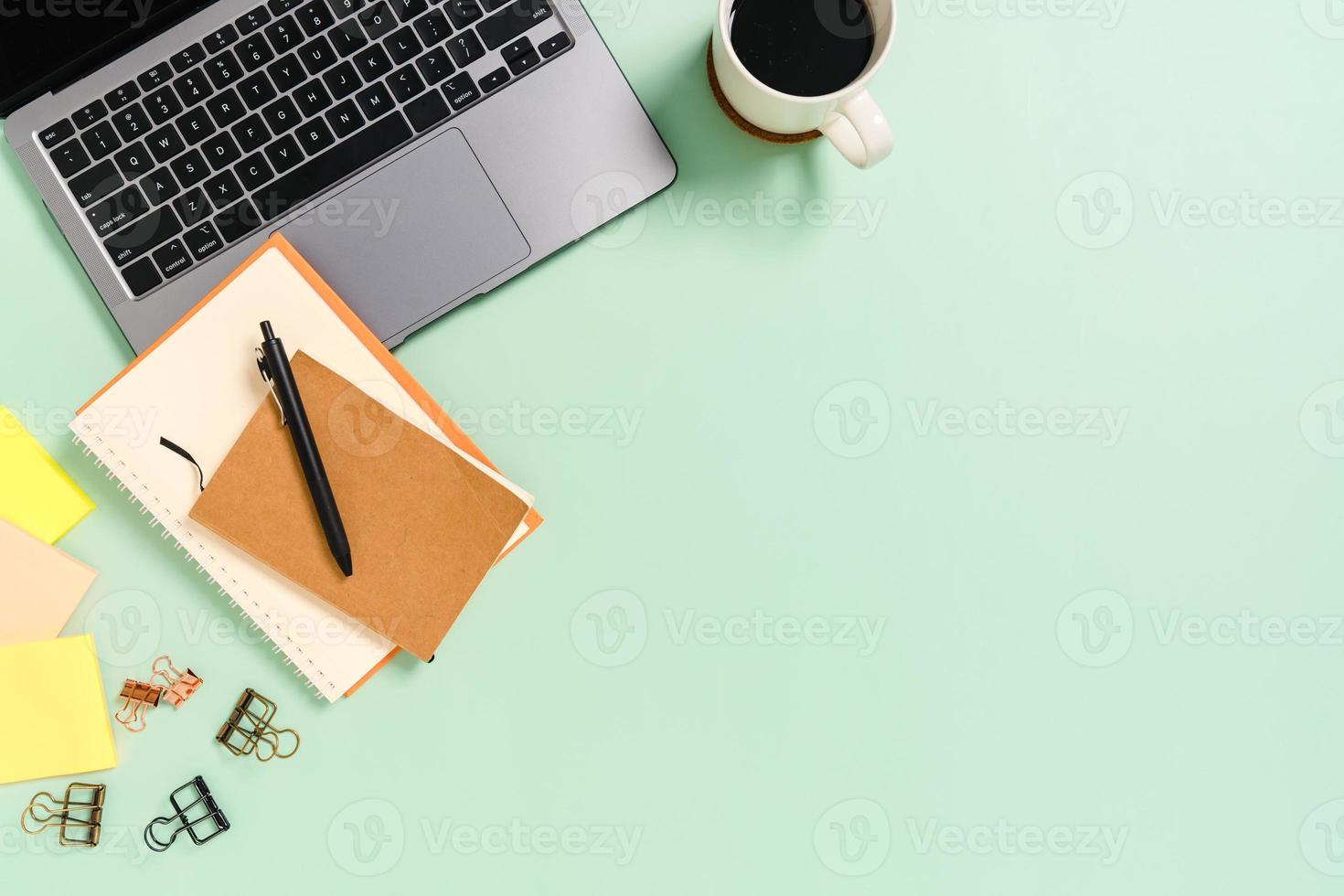 minimaler arbeitsplatz - kreatives flaches foto des arbeitsplatzes. Schreibtisch von oben mit Laptop, Kaffeetasse und Notizbuch auf pastellgrünem Hintergrund. Draufsicht mit Kopienraumfotografie.