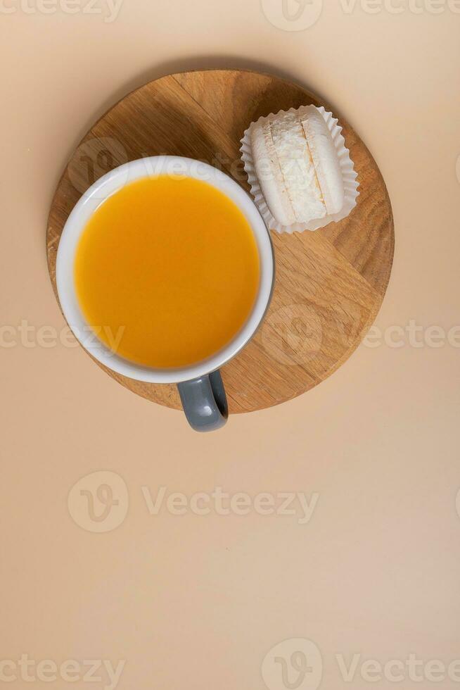 Tasse von Meer Sanddorn Tee und Makrone eben legen, oben Aussicht auf Beige Hintergrund foto