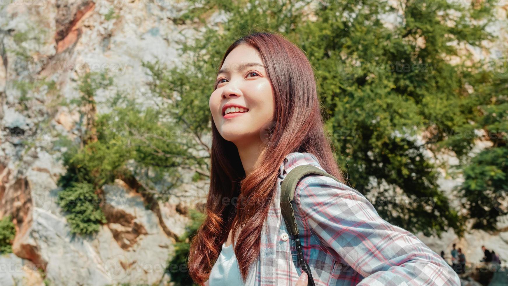 fröhliche junge reisende asiatische dame mit rucksack, die am bergsee spaziert. koreanisches jugendlich mädchen genießen ihr urlaubsabenteuer und fühlen sich glücklich freiheit. Lifestyle-Reisen und Entspannung im Freizeitkonzept. foto