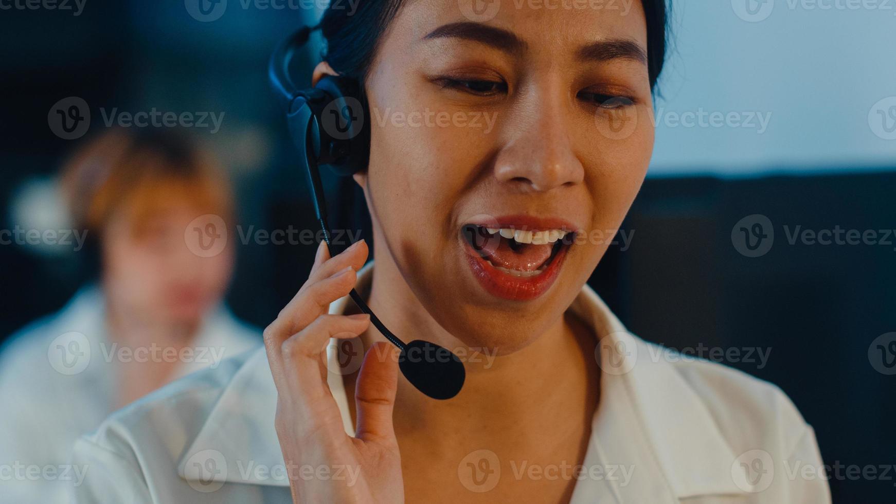 Nahaufnahme des jungen Call-Center-Teams in Asien oder des Kundendienstmitarbeiters, der Computer- und Mikrofon-Headset verwendet, das den technischen Support im Late-Night-Büro verwendet. Telemarketing- oder Verkaufsjobkonzept. foto