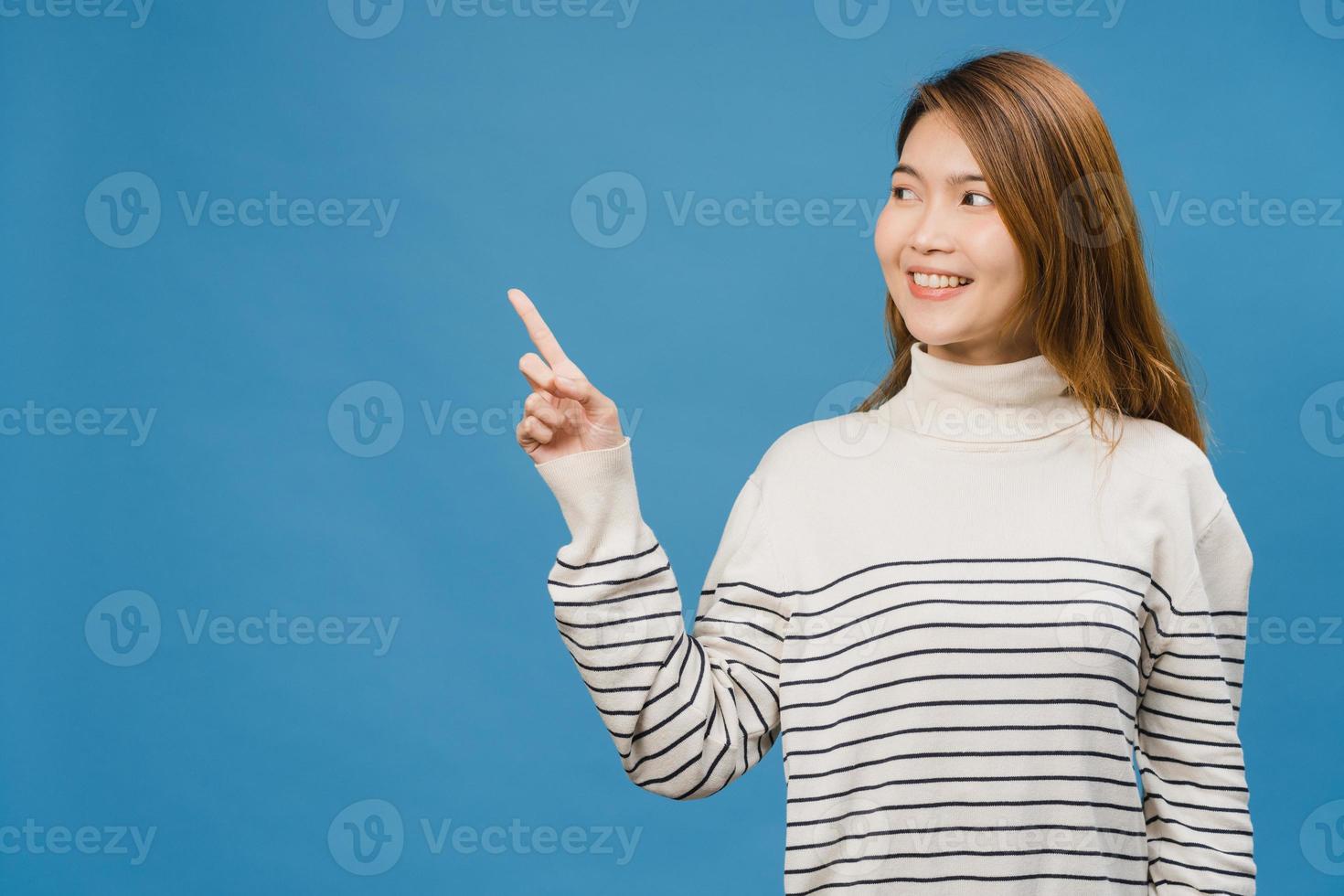 Porträt einer jungen asiatischen Dame, die mit fröhlichem Ausdruck lächelt, zeigt etwas Erstaunliches an leeren Stellen in Freizeitkleidung und steht einzeln auf blauem Hintergrund. Gesichtsausdruck Konzept. foto