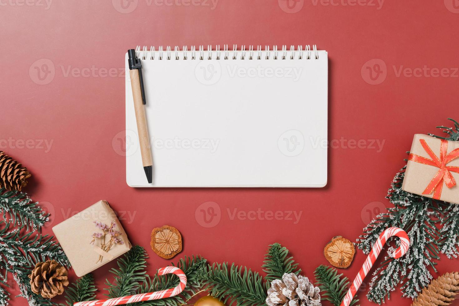 minimale kreative flache Lage der traditionellen Winterweihnachtskomposition und der Neujahrsferienzeit. Ansicht von oben offenes Mockup schwarzes Notizbuch für Text auf rotem Hintergrund. Mock-up und kopieren Sie Raumfotografie. foto