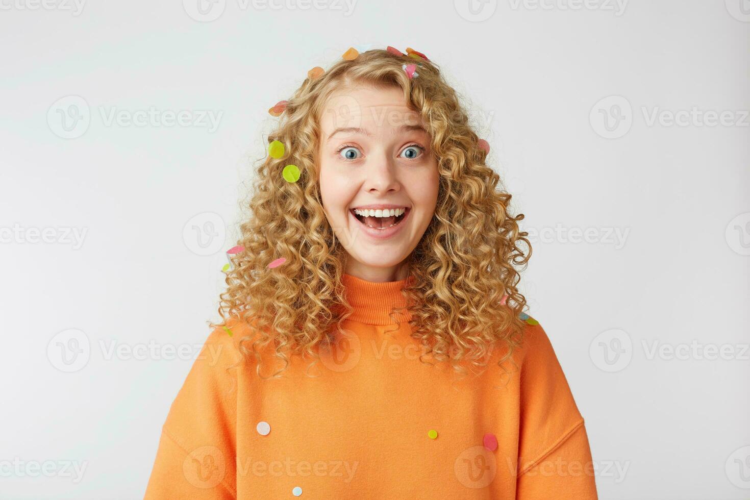 überrascht froh inspiriert blond mit breit öffnen Blau Augen glücklich lächelnd fühlt sich froh zufrieden gekleidet im ein Orange übergroß Sweatshirt isoliert auf ein Weiß Hintergrund foto