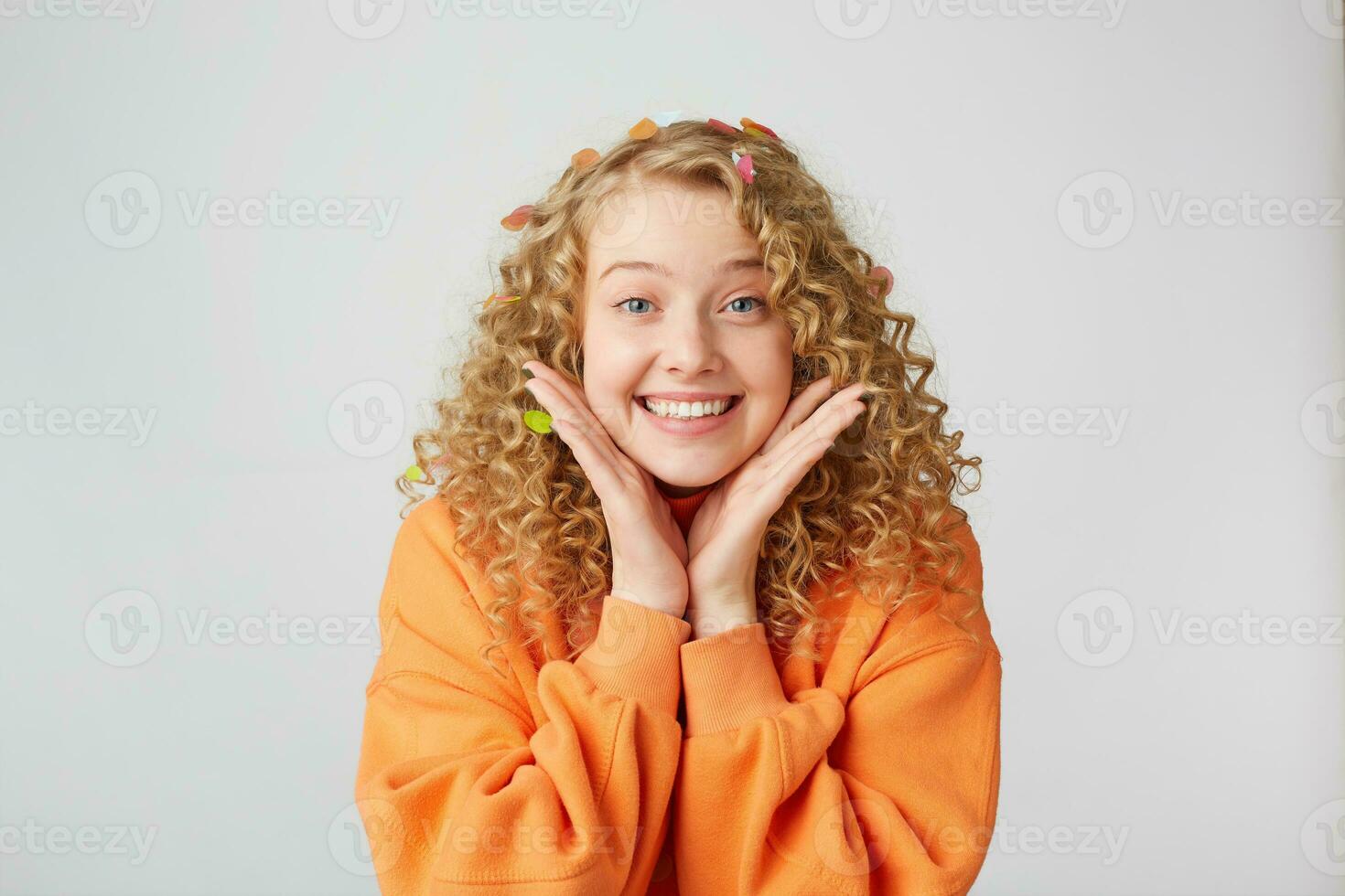 Porträt von schön zärtlich nett blond sieht aus aufgeregt, überrascht, hält Palmen in der Nähe von Gesicht, gekleidet im übergroß Orange Pullover, isoliert auf ein Weiß Hintergrund foto