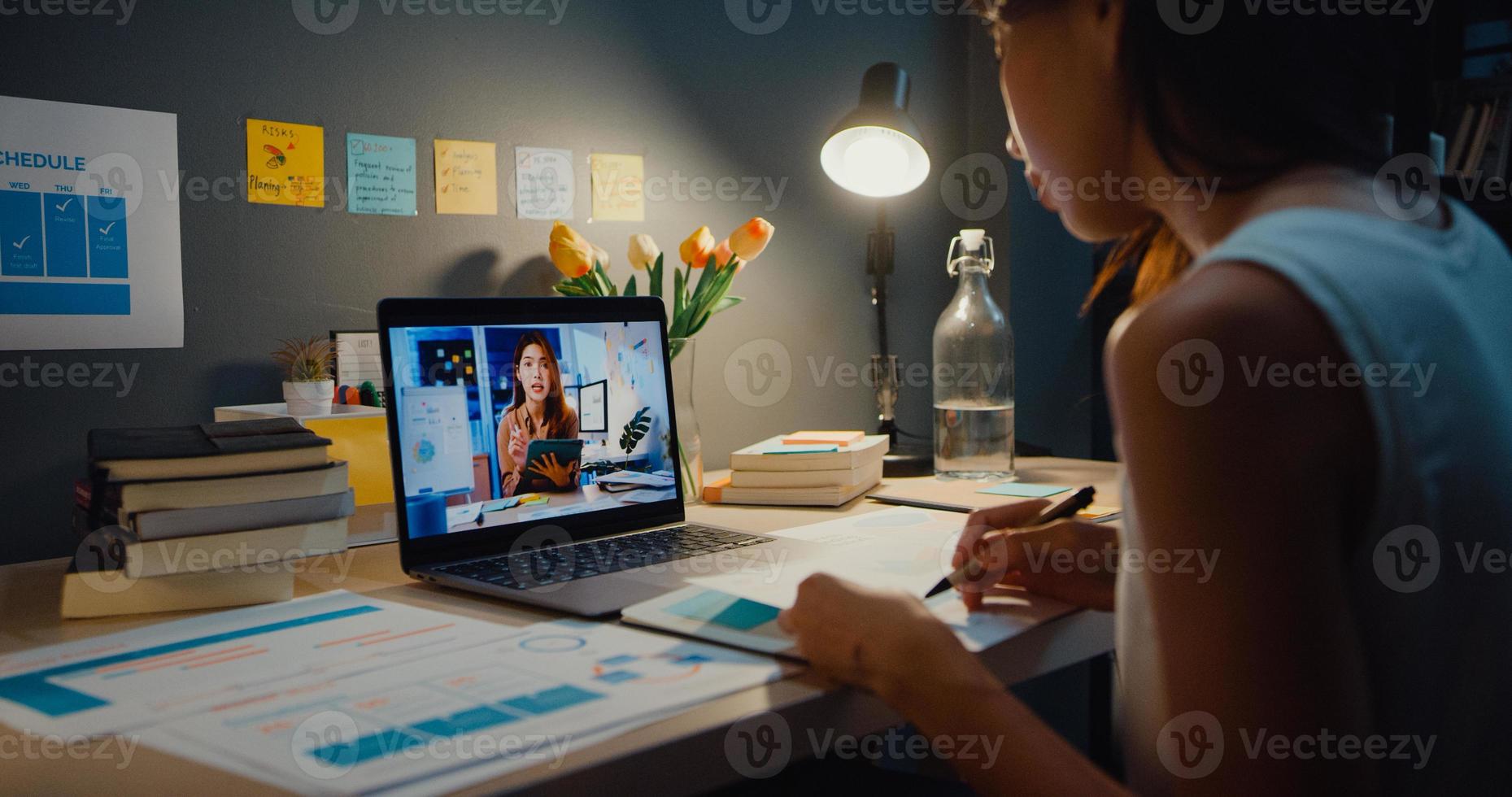 Asiatische Geschäftsfrau, die Laptop verwendet, spricht mit Kollegen über den Plan in einem Videoanruf-Meeting im Wohnzimmer zu Hause. Arbeiten von Hausüberlastung in der Nacht, aus der Ferne, soziale Distanz, Quarantäne für Coronavirus. foto