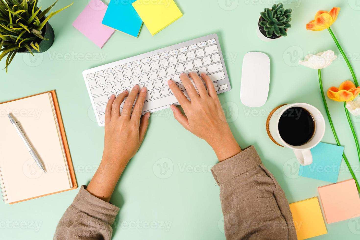 kreatives flaches Laienfoto des Arbeitsplatzschreibtisches. Schreibtisch von oben mit Tastatur, Maus und offenem schwarzen Notizbuch auf pastellgrünem Hintergrund. Draufsichtmodell mit Kopienraumfotografie. foto