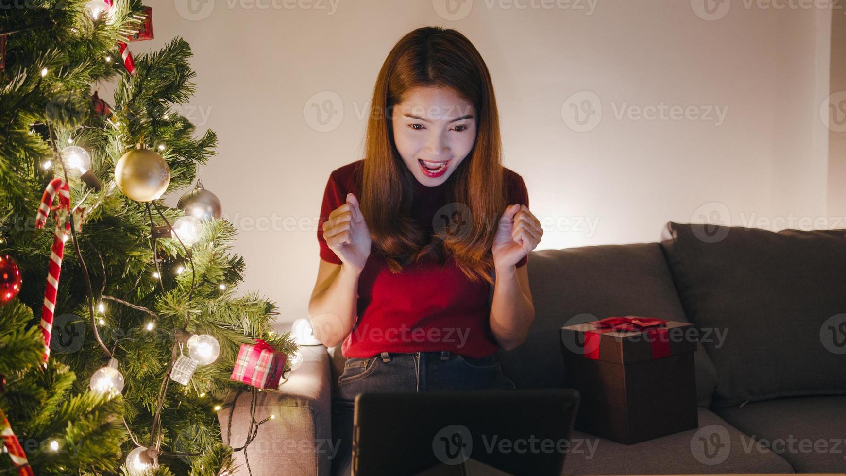 Junge Asiatin mit Tablet-Videoanruf im Gespräch mit Paar, Weihnachtsbaum mit Ornament auf dem Sofa im Wohnzimmer zu Hause geschmückt. soziale Distanzierung, Weihnachtsnacht und Neujahrsfest. foto