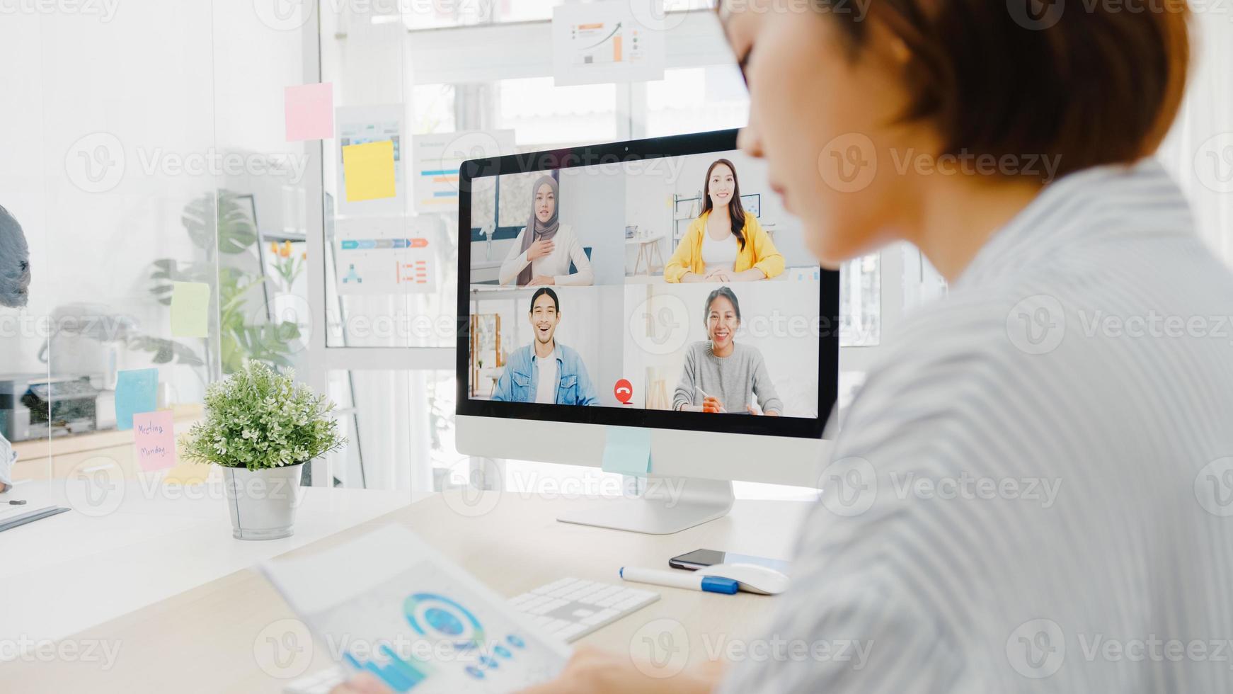 asiatische Geschäftsleute, die Desktop verwenden, sprechen mit Kollegen, die ein Geschäfts-Brainstorming über den Plan in einem Videoanruf-Meeting in einem neuen normalen Büro diskutieren. Lebensstil soziale Distanzierung und Arbeit nach dem Coronavirus. foto