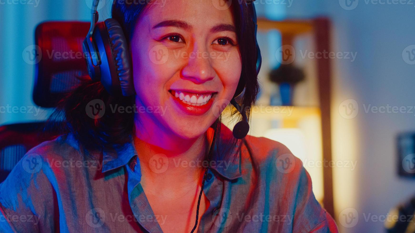 Happy Asia Professional Girl Gamer tragen Kopfhörer Teilnahme spielen Videospiel bunte Neonlichter Computer im Wohnzimmer zu Hause. Esport-Streaming-Spiel online, Heimquarantäne-Aktivitätskonzept. foto