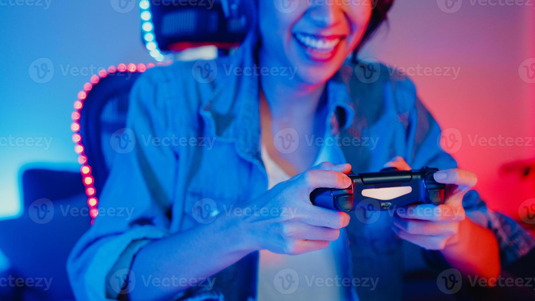 Happy Asia Girl Gamer tragen Kopfhörer und Joystick-Controller, sprechen mit einem Freund, fühlen sich lustig und aufgeregt mit einem Online-Wettbewerbsspiel im Neon-Wohnzimmer-Heimstudio in der Nacht, Heimquarantäne-Aktivität. foto