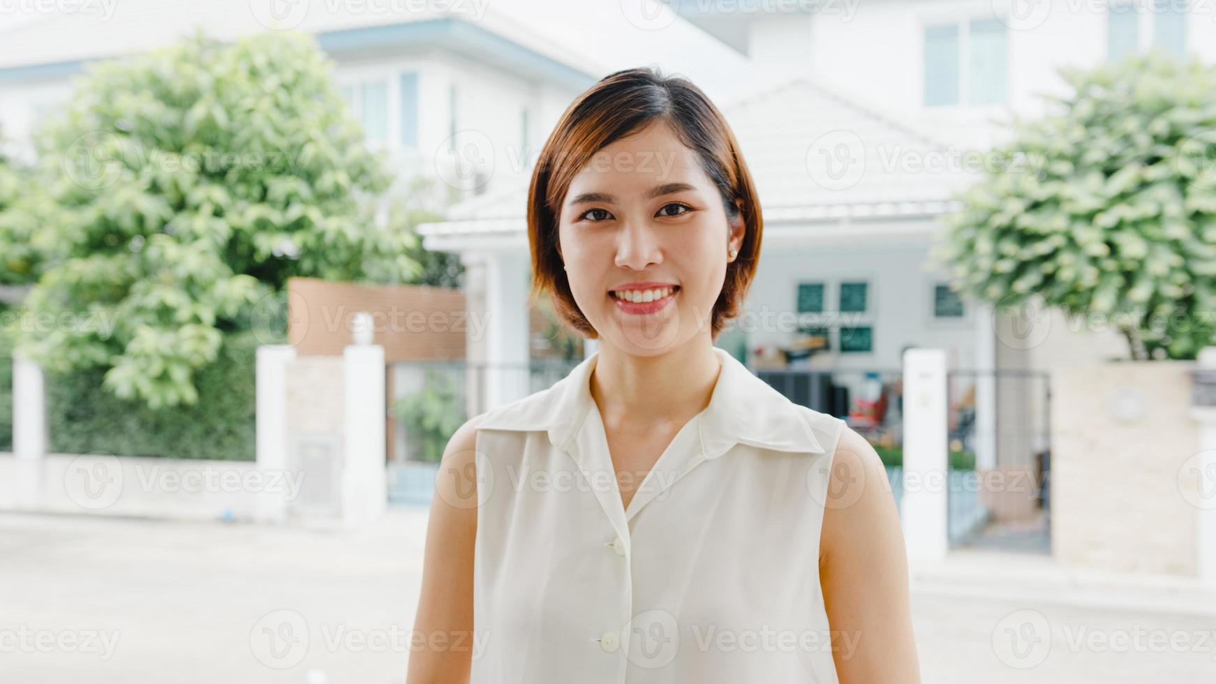 glückliche junge asiatische frau, die glücklich lächelt und zur kamera schaut, während sie sich auf der straße in der modernen stadt entspannt. Lifestyle-Frau am Außenhauskonzept. foto