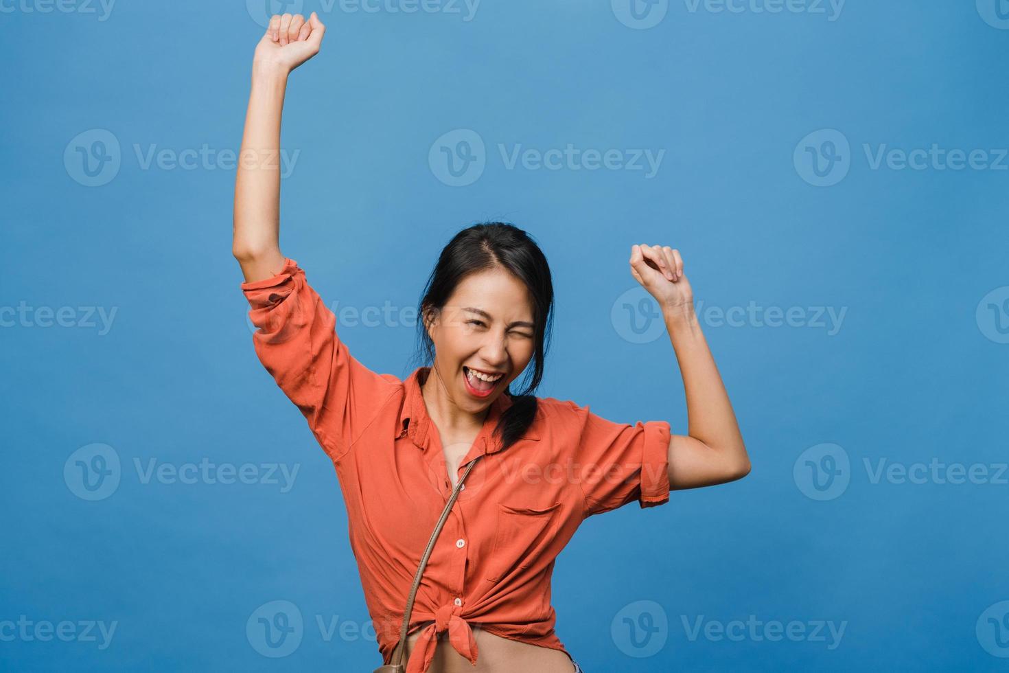 junge asiatische dame mit positivem ausdruck, fröhlich und aufregend, gekleidet in lässiges tuch über blauem hintergrund mit leerem raum. glückliche entzückende frohe frau freut sich über erfolg. Gesichtsausdruck Konzept. foto