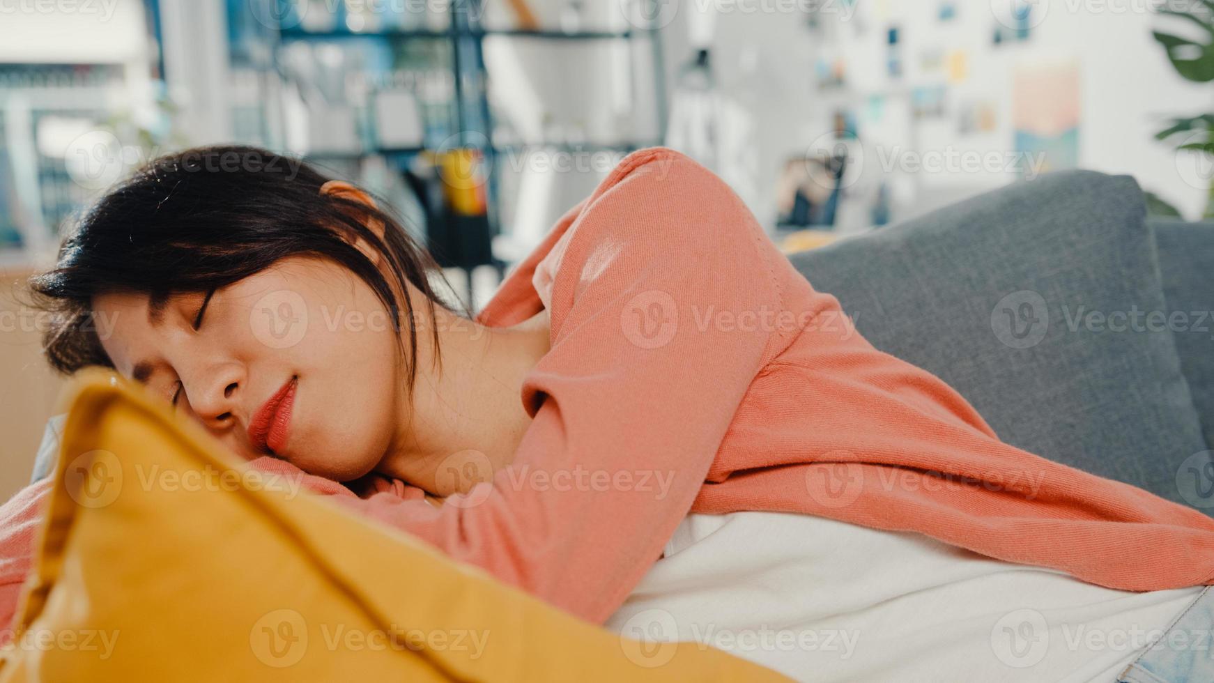 Schöne asiatische Dame fühlt sich entspannt auf dem Sofa mit Kissen zu Hause hinlegen. zu Hause bleiben, eine Pause von der Arbeit machen, in der Komfortzone zu Hause entspannen, sich zu Hause ausruhen, Abstand halten, Covid-Quarantäne-Konzept. foto